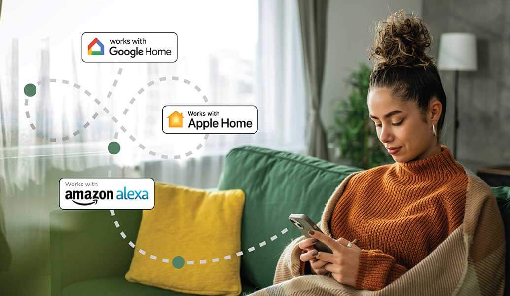 Woman using a smartphone with connectivity logos for Google Home, Apple Home, and Amazon Alexa in a living room setting.