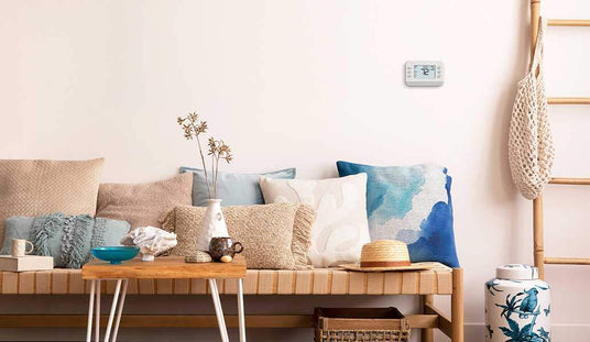 An X series thermostat is on a living room wall.