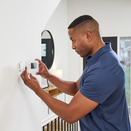 A professional installer installs a smart thermostat.
